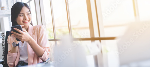 Cute Asian girl sending social emoji smiling by mobile phone at coffee shop in the morning.	
