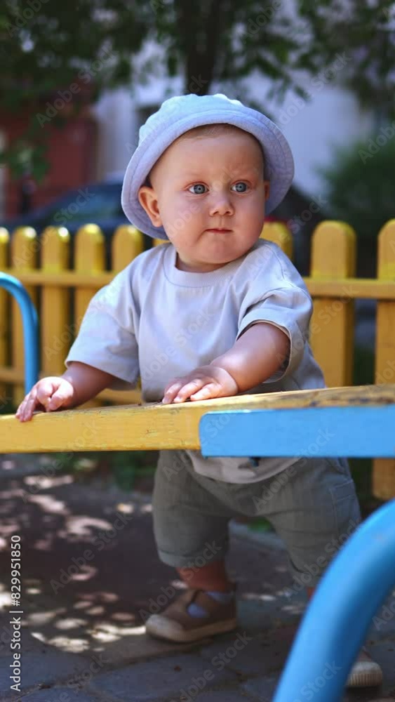 A baby boy in a linen panama is playing on the street. Stylish baby boy in summer clothes. A baby boy in a linen panama is playing on the street. Stylish baby boy in summer clothes.