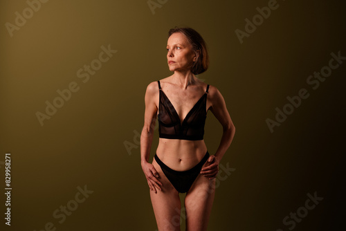 Photo of lovely senior lady look empty space dressed black lingerie brown background no filter self acceptance all body perfect