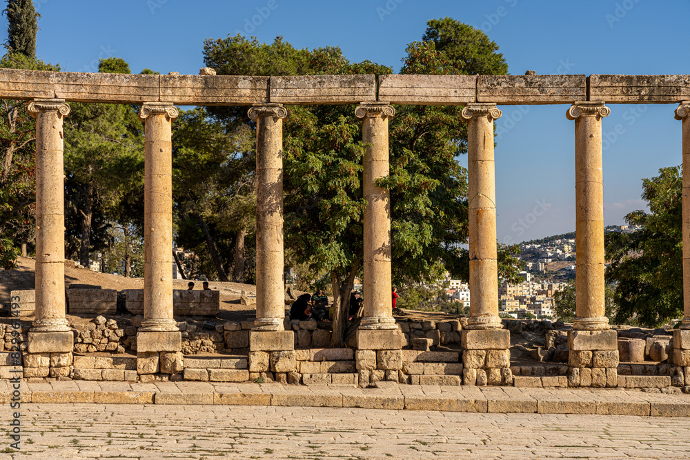 Fototapeta premium Ancient Forum of Gerash, Jordan: Majestic Roman Columns Amidst Scenic Landscape and Historic Ruins
