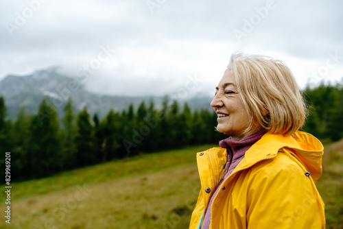 Close up portrait Smiling Caucasian Senior woman in yellow rain jacket in Misty autumn mountain landscape. Concept: Travel, Lifestyle, Freedom and joy in retirement.  © Natalia Shmatova