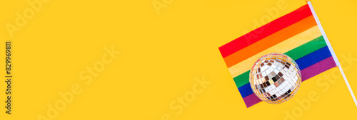 LGBT rainbow flag and disco ball flat lay on yellow color background. gay marriage, human rights, june parade, lgbtq proud history month concept, coming out day. top view, place for text or logo photo