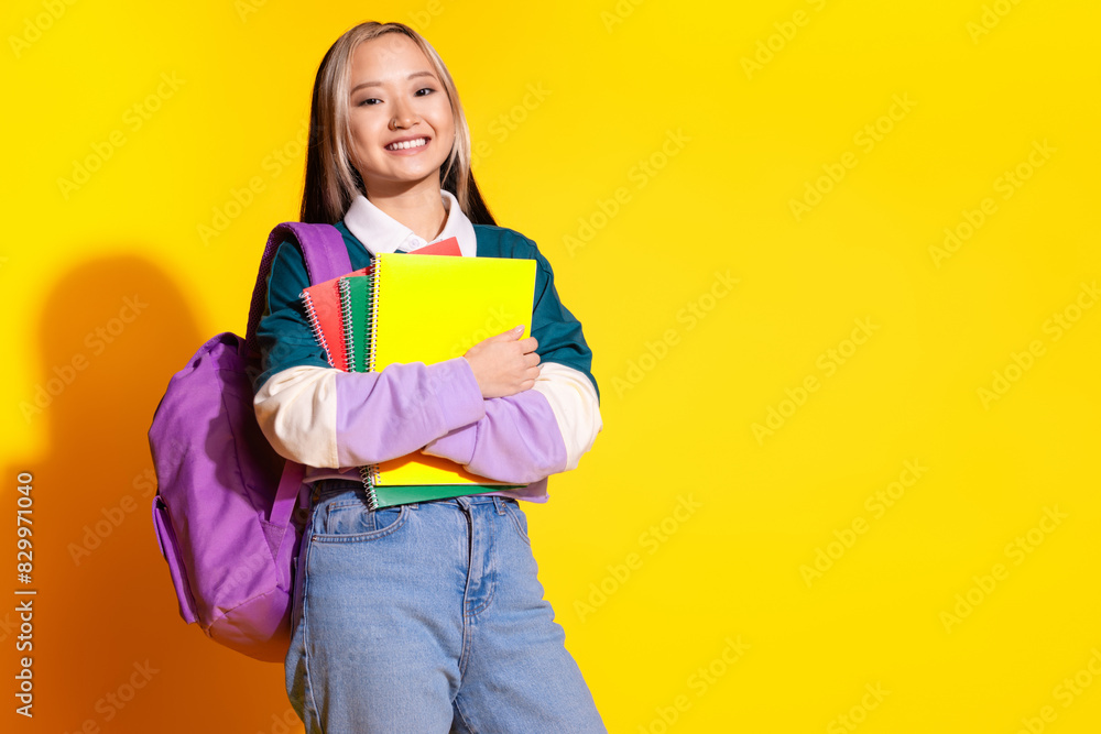 Photo of diligent korean girl with dyed hairstyle dressed striped shirt holding copybook isolated on vivid yellow color background Photo of diligent korean girl with dyed hairstyle dressed striped shirt holding copybook isolated on vivid yellow color background