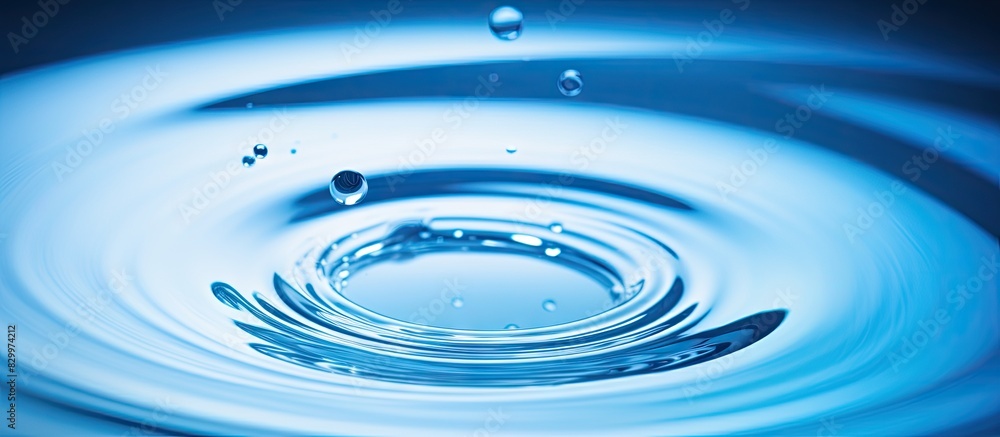 A blue water droplet falls into the water creating concentric circles and reflecting a blue wave Copy space image A blue water droplet falls into the water creating concentric circles and reflecting a blue wave Copy space image