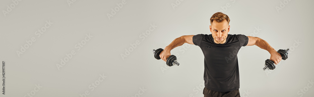 A young sportsman in active wear performs a handstand on a grey background in a studio setting. A young sportsman in active wear performs a handstand on a grey background in a studio setting.