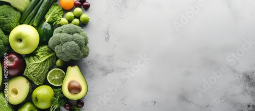 Copy space image of fresh and green vegetables and fruits including lettuce cucumbers green onions avocados and green apples arranged on a gray concrete surface This composition represents the concep photo