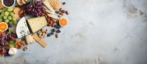 A diverse assortment of wine snacks arranged artistically on a textured grey concrete backdrop The top down view showcases a variety of cheeses jam fresh fruit nuts and crackers This visually strikin photo