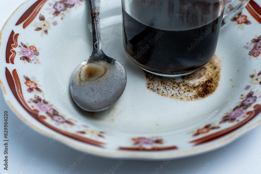 A glass of coffee and a spoon on a plate
A glass of coffee and a spoon on a plate