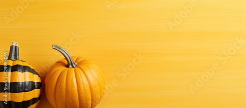 Autumn themed flat lay with a small striped pumpkin placed on yellow paper The image conveys the essence of the fall season harvest Thanksgiving and Halloween with a copy space image photo