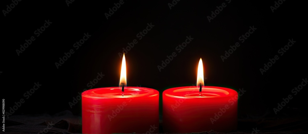 A black background with two red candles burning providing a copy space image for text A black background with two red candles burning providing a copy space image for text