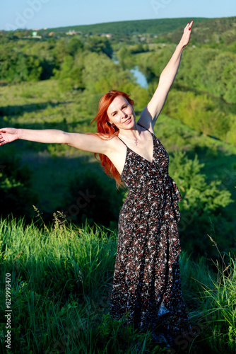 A girl in a red blouse and white jeans poses for the camera in nature. Joy, happiness, serenity. A girl poses for a photographer in nature.