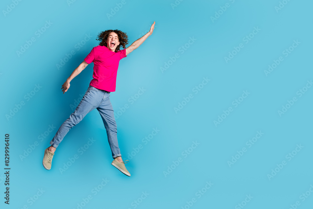 Full length portrait of nice young man jumping empty space wear t-shirt isolated on blue color background