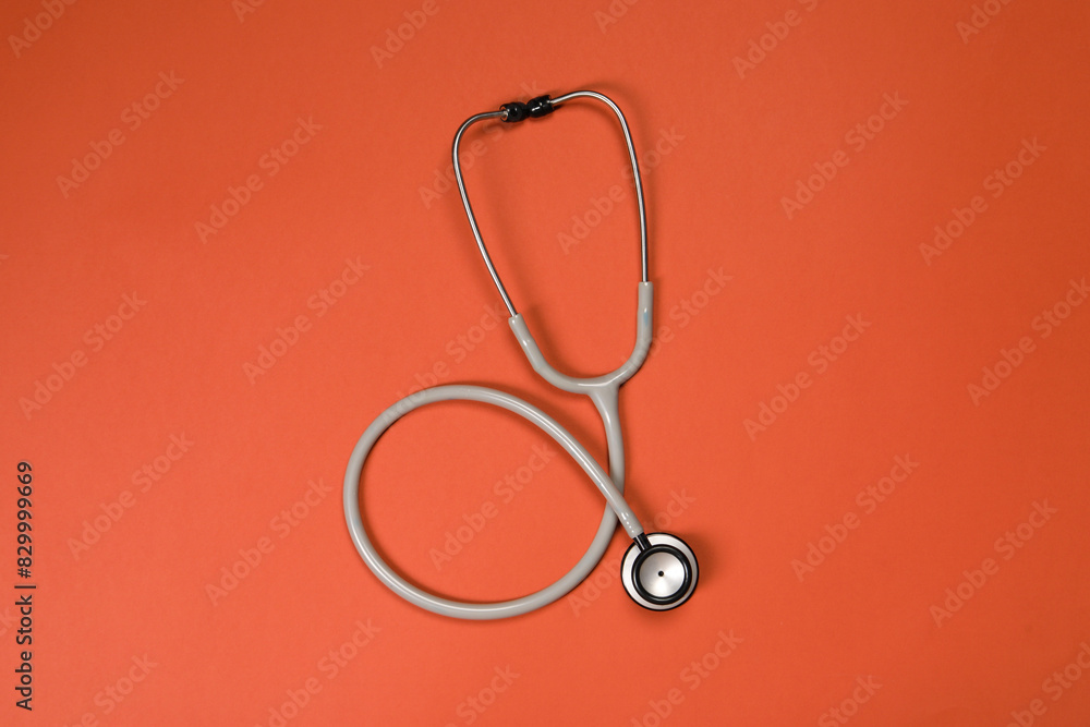 One stethoscope on crimson background, top view. Medical tool One stethoscope on crimson background, top view. Medical tool