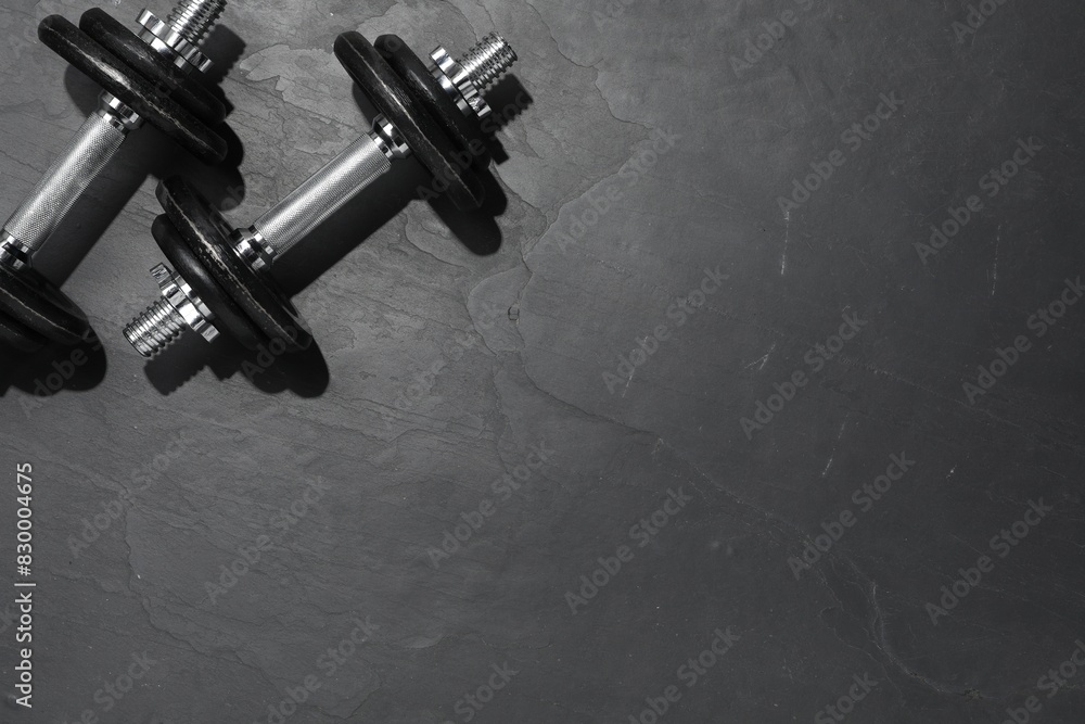 Barbells on dark textured floor, top view. Space for text Barbells on dark textured floor, top view. Space for text