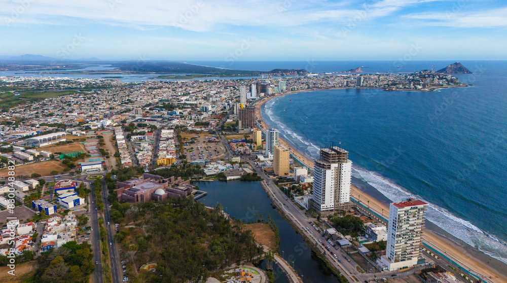 Fototapeta premium An aerial view of Mazatlán Beach on a sunny morning, showcasing the blue ocean's gentle waves meeting the sandy shores of this popular tourist destination