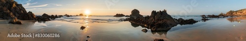 A beautiful beach with rock formations and tide pools  with the setting sun reflecting off the water. The tropical setting creates a stunning backdrop for a summer vacation.