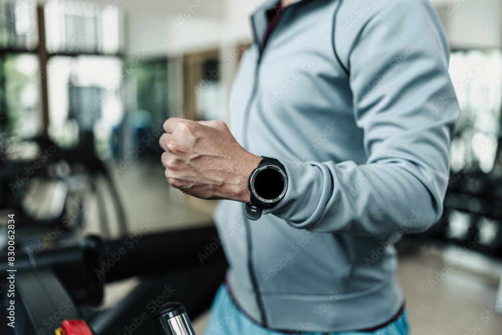 A man wearing smart watch and running on track treadmill, exercise fitness. Fitness, gym, workout and lifestyle concept. A man wearing smart watch and running on track treadmill, exercise fitness. Fitness, gym, workout and lifestyle concept.