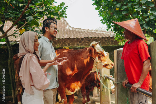 Fényképezés Young Asian Muslim couple doing negotiation with the cattleman buying livestock cows for sacrifices