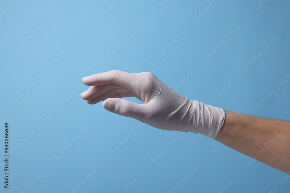 Doctor wearing white medical glove on light blue background, closeup Doctor wearing white medical glove on light blue background, closeup