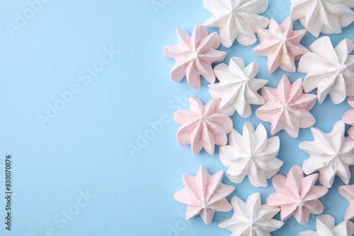 Tasty meringue cookies on light blue background  flat lay. Space for text