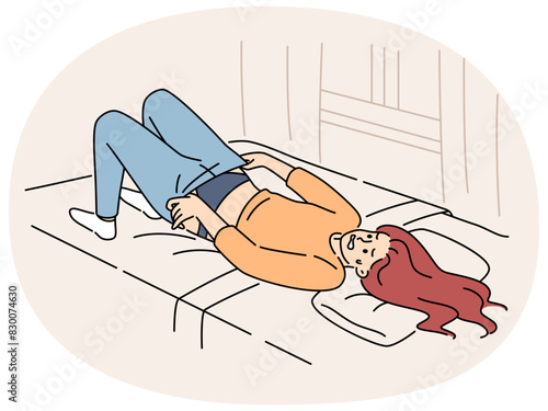 Overweight woman tries in vain to put on small pants lying on bed in bedroom of apartment. Overweight young girl needs help of nutritionist or fitness trainer to reduce waist and hips