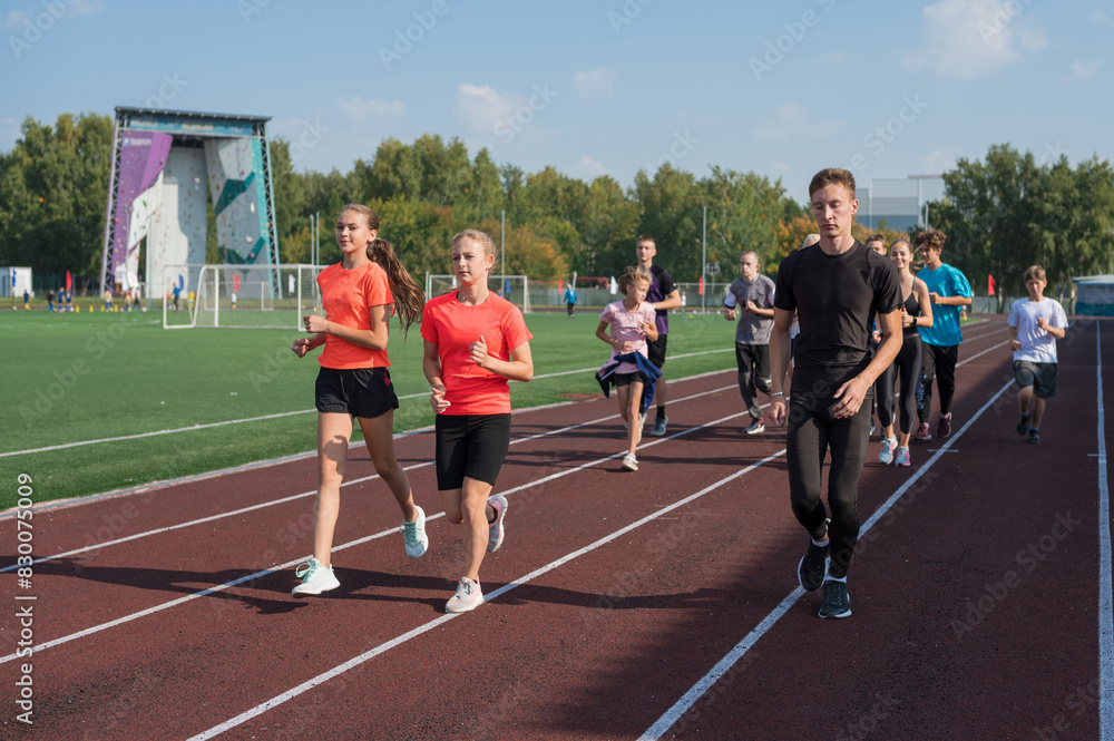 Obraz premium Group of young athletes training at the stadium. School gym trainings or athletics