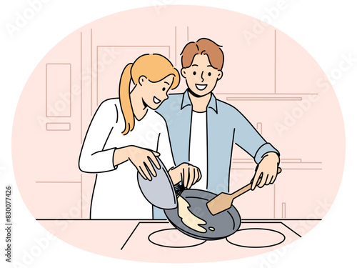 Married couple prepares breakfast enjoying sunday morning and experiencing happiness from communicating with loved one. Happy couple of man and woman cooking pancakes or omelet together