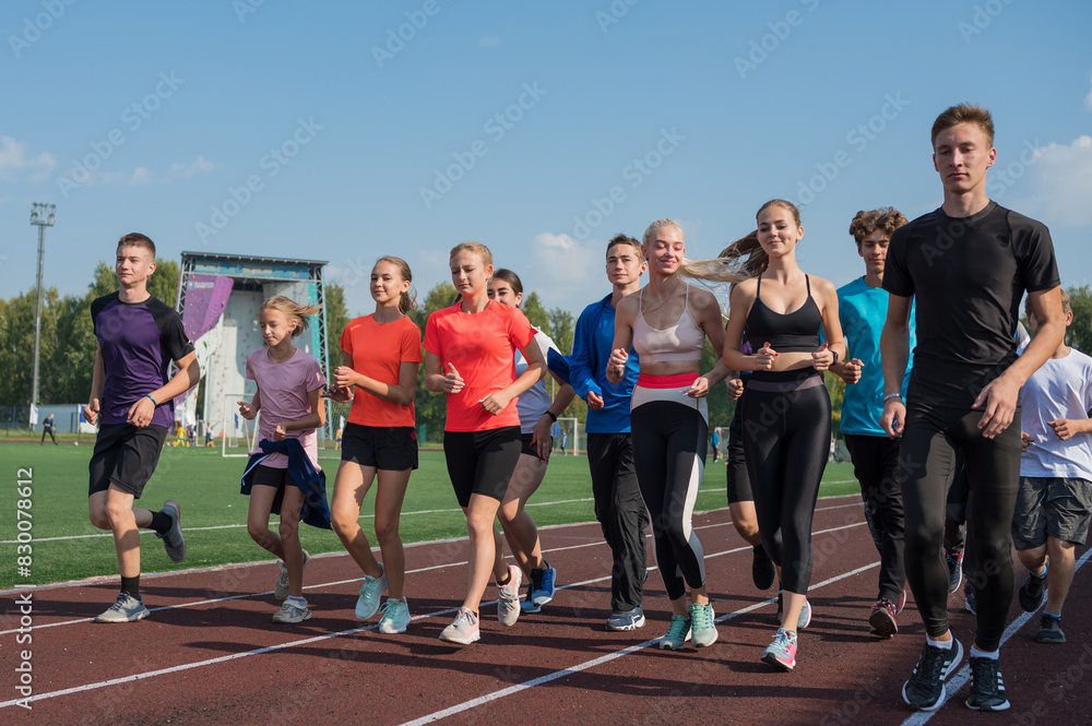 Fototapeta premium Group of young athletes training at the stadium. School gym trainings or athletics