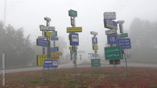 Almhult, Sweden A traffic circle in the fog with road signs in multiple languages including Russian, Thai, and Arabic. photo