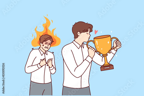 Envy overcomes business man looking at colleague kissing trophy cup for professional skills. Guy with flame above head gets angry out of envy at competitor, managed to achieve success in career