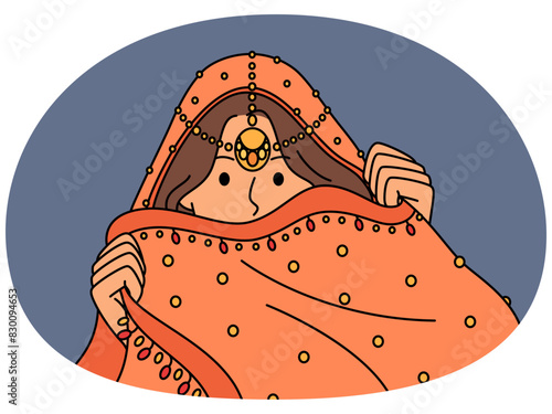 Indian woman hides face behind national dress during traditional cultural ritual or ethnic wedding. Hindu girl model in Indian saree clothes with precious jewelry hiding wanting to intrigue partner