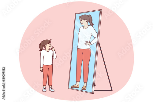 Little girl stands and looks in mirror, saw reflection of adult woman and dreams of becoming adult as soon as possible. Preteen girl wants to be as beautiful as mother or older sister