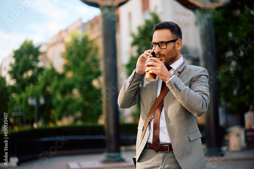 Smiling entrepreneur drinking takeaway coffee while talking on the phone in the city.