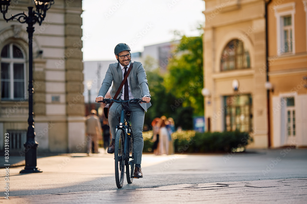 Happy businessman riding bicycle in city.