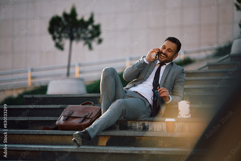 Cheerful businessman talking on mobile phone during lunch break in city.