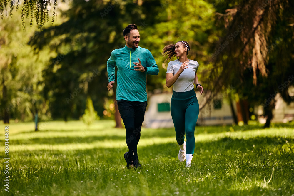 Happy athletic couple talking while jogging in park. Happy athletic couple talking while jogging in park.