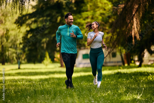 Happy athletic couple talking while jogging in park.