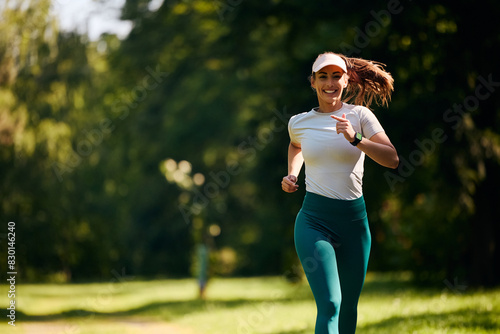 Happy female athlete running in park. © Drazen