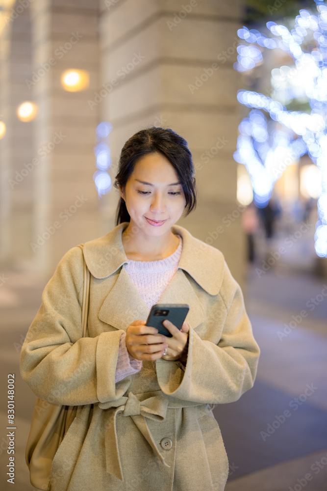 Fototapeta premium Woman use on mobile phone and walk along the street at night