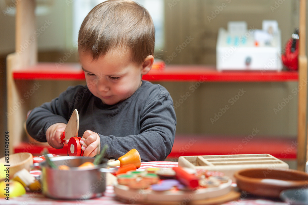 Toddler concentrating on his cooking game. Symbolic and imaginative play. Toddler concentrating on his cooking game. Symbolic and imaginative play.