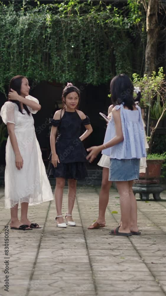 Four Asian teenage girls forming a circle in the garden with smartphone in hand chatting and laughing calmly slow motion Four Asian teenage girls forming a circle in the garden with smartphone in hand chatting and laughing calmly slow motion
