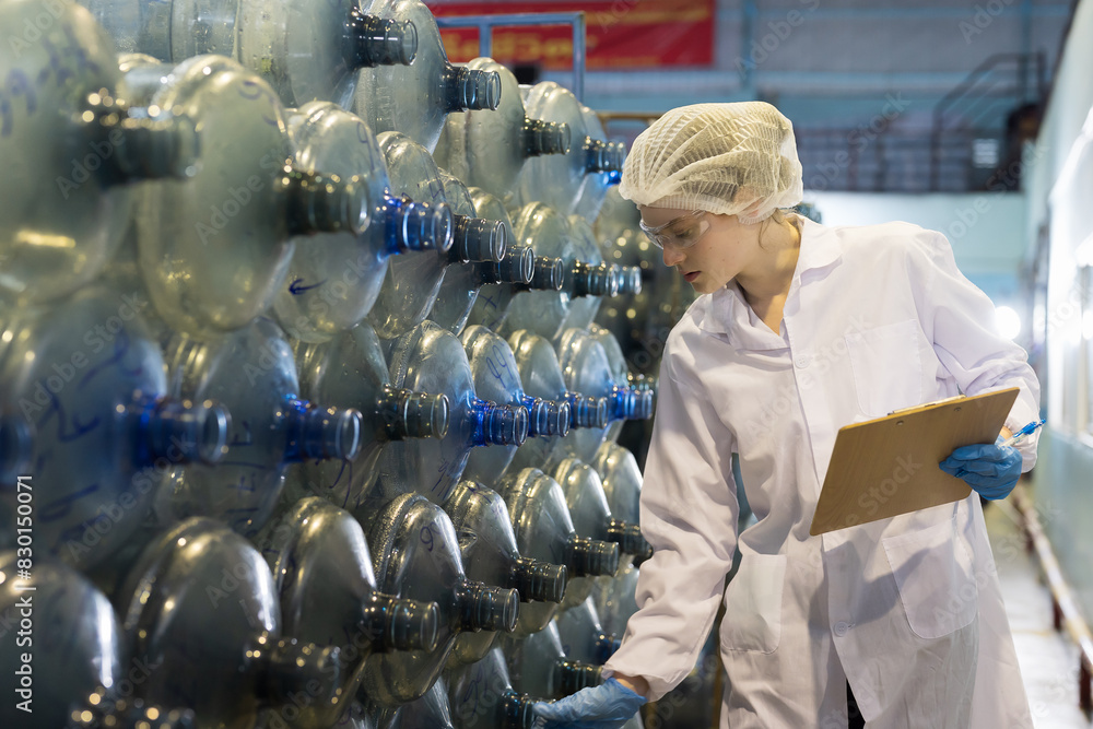 Female worker inspecting quality of plastic drinking water tank in ...