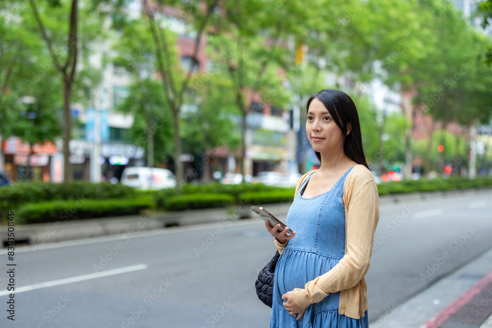 Pregnant woman use cellphone to order taxi in the city Pregnant woman use cellphone to order taxi in the city