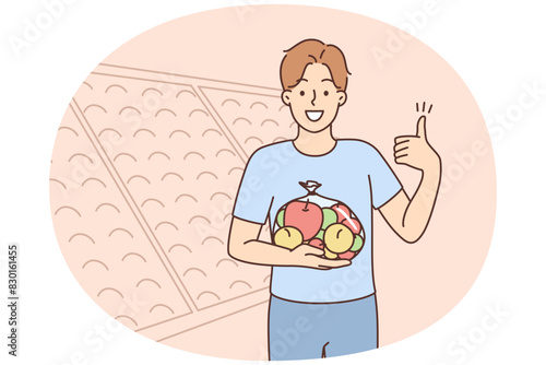Smiling man with bag of apples in supermarket