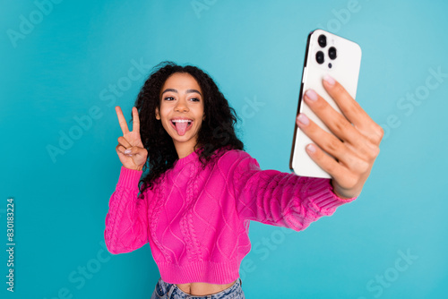 Photo portrait of lovely teen lady selfie photo v-sign stick tongue dressed stylish pink garment isolated on cyan color background © deagreez