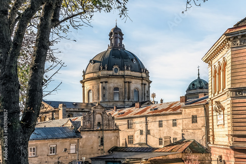 View of the ancient architecture of Lviv with the dome of The Dominican church and monastery through the branches of autumn trees. Facades of ancient buildings close-up