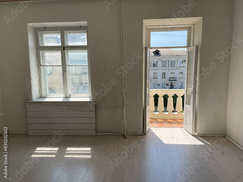 Interior of an empty white room with a window and a balcony