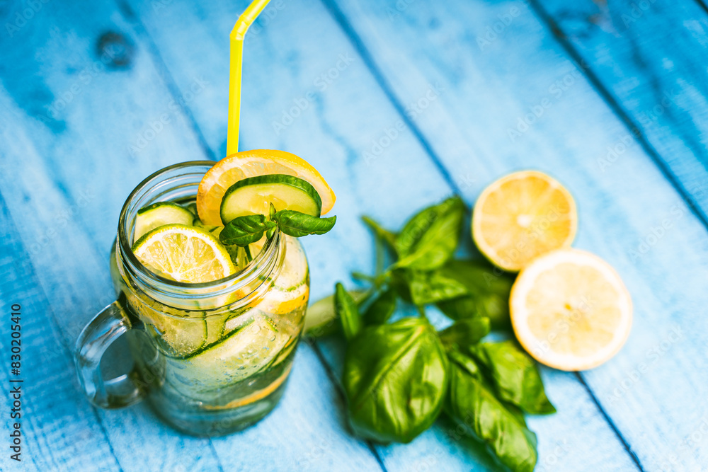 Fototapeta premium A fresh cocktail of basil, cucumber, lemon and lime in a transparent mug on a blue wooden table. Diet Drink, Selected Focus.