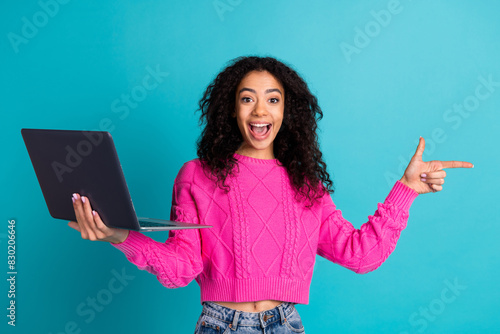 Photo portrait of attractive teen girl hold netbook point empty space dressed stylish pink clothes isolated on aquamarine color background