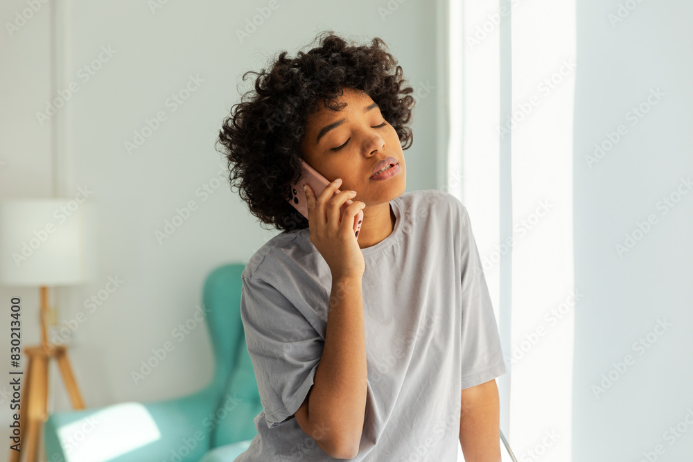 African american girl talking on smartphone at home indoor. Young woman with cell phone chatting with friends. Smiling teen girl making answering call by cellphone. Lady having conversation by mobile African american girl talking on smartphone at home indoor. Young woman with cell phone chatting with friends. Smiling teen girl making answering call by cellphone. Lady having conversation by mobile